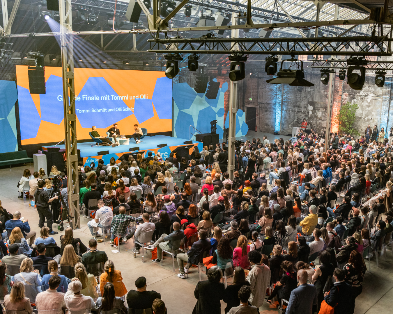 Main stage of All Ears by Spotify, featuring a big crowd and hexagon shapes and a bold orange.